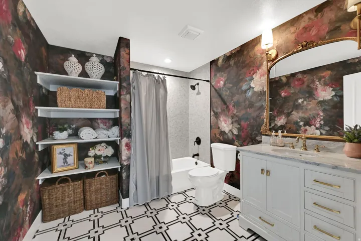 Bathroom featuring a single-sink vanity with a light-colored countertop and brass-finish faucet, a toilet, and a shower-tub combination