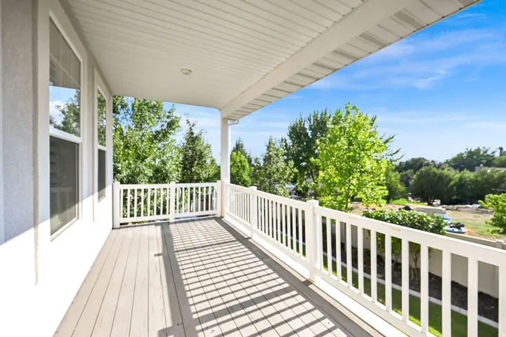 Covered balcony featuring wood-finish decking and white railing