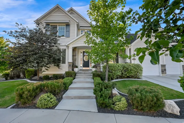 Light-toned siding exterior with stone accents, a covered entry, and a concrete walkway