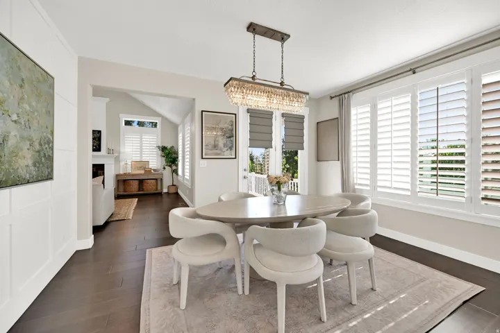 Dining area featuring wood-finish flooring, white paneling, and an ornate chandelier