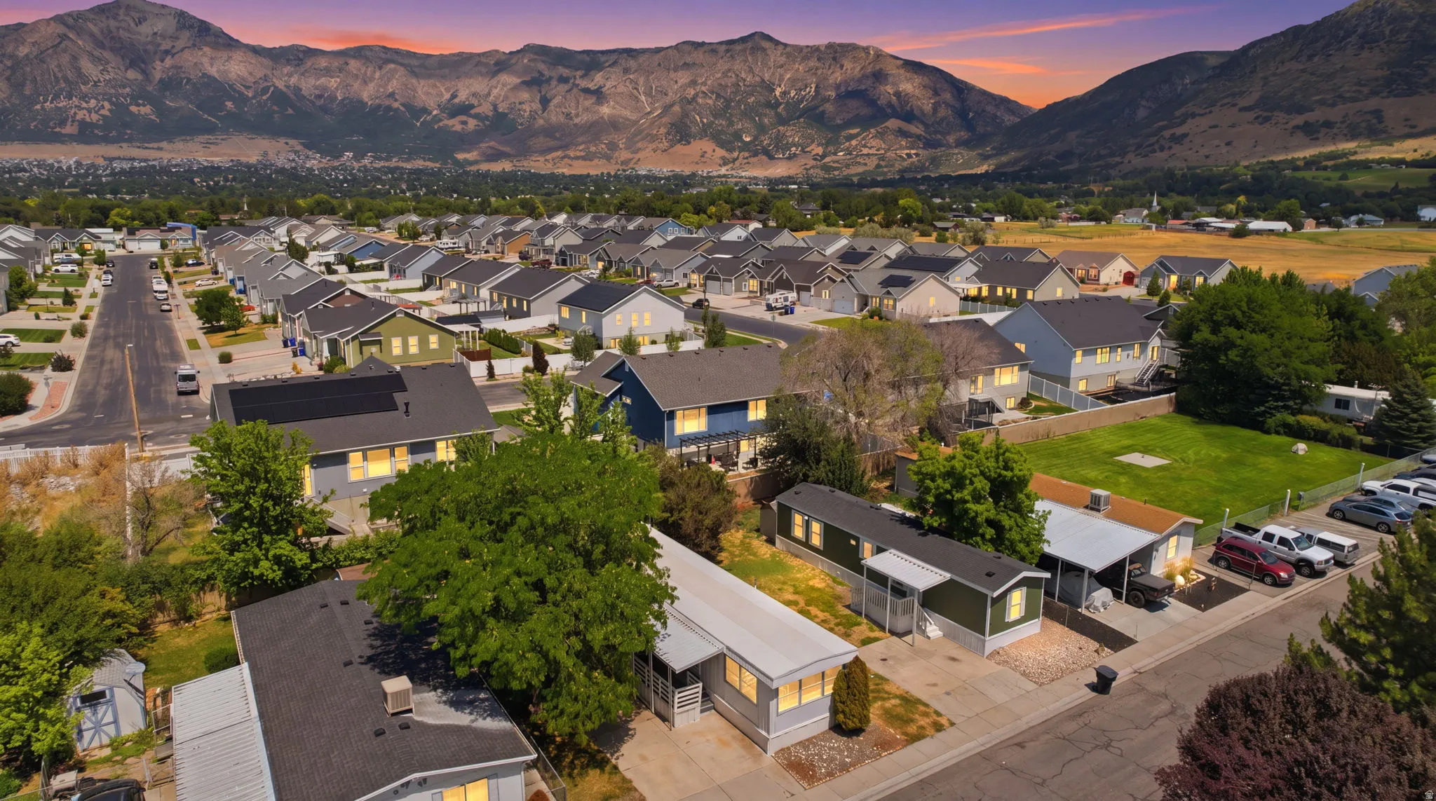 Established neighborhood featuring a collection of single-family homes, mature trees, and paved streets, all set against a prominent mountain backdrop