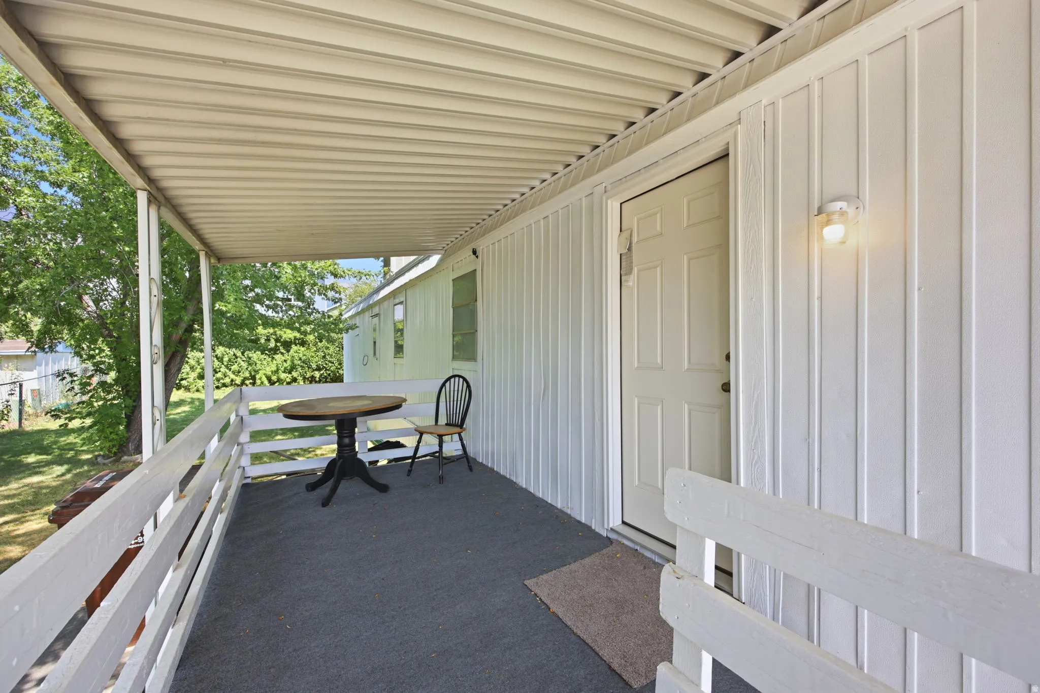 Covered porch with a textured gray surface, white painted railings, and a white board-and-batten exterior