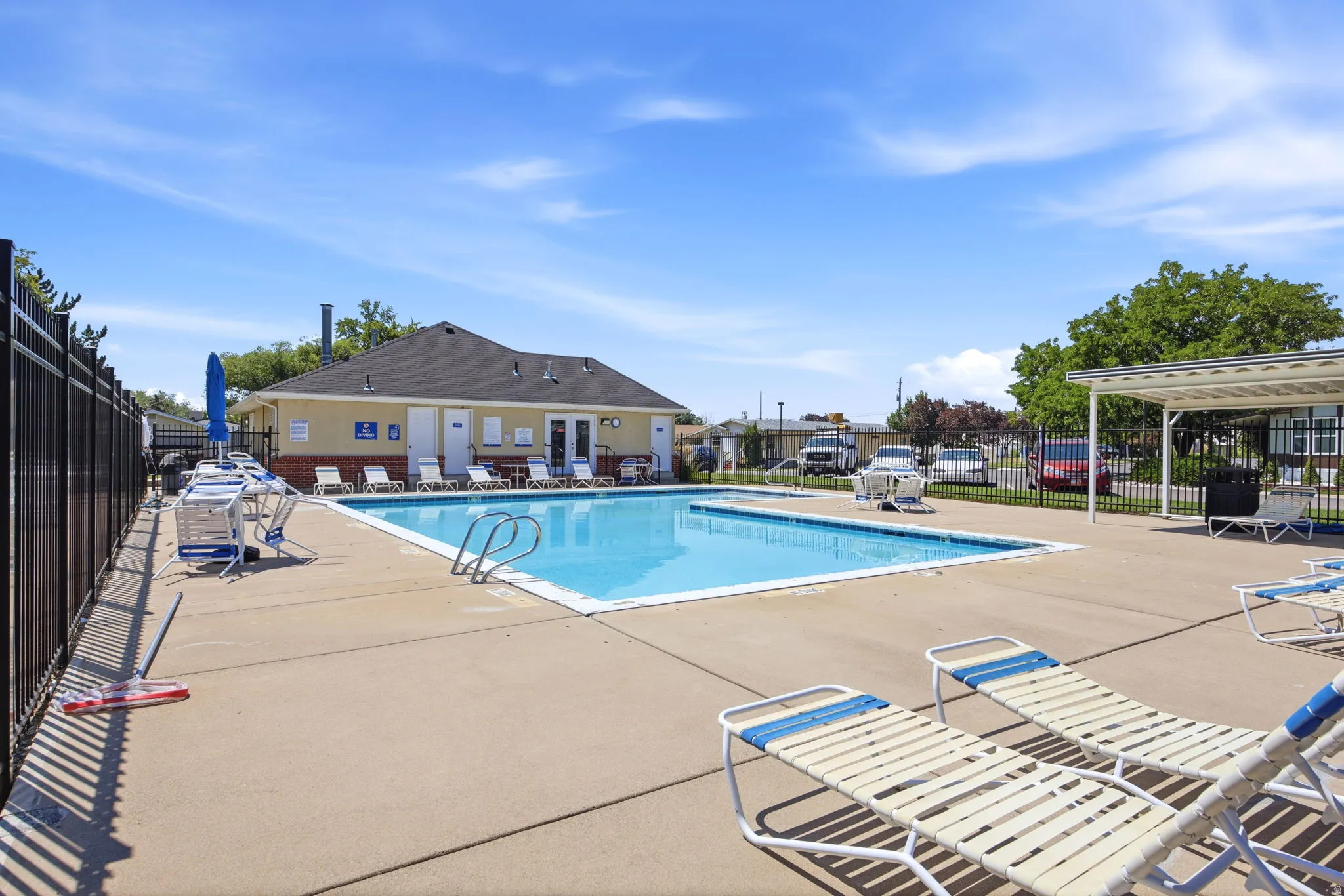 Resort-style swimming pool with spacious concrete decking, lounge seating areas, and a pergola-covered pavilion