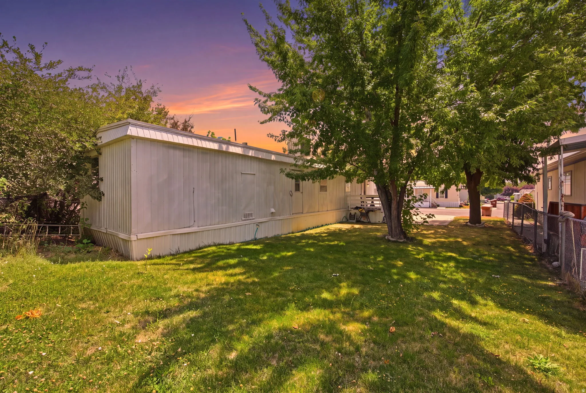 Spacious side yard featuring mature trees and a manicured lawn