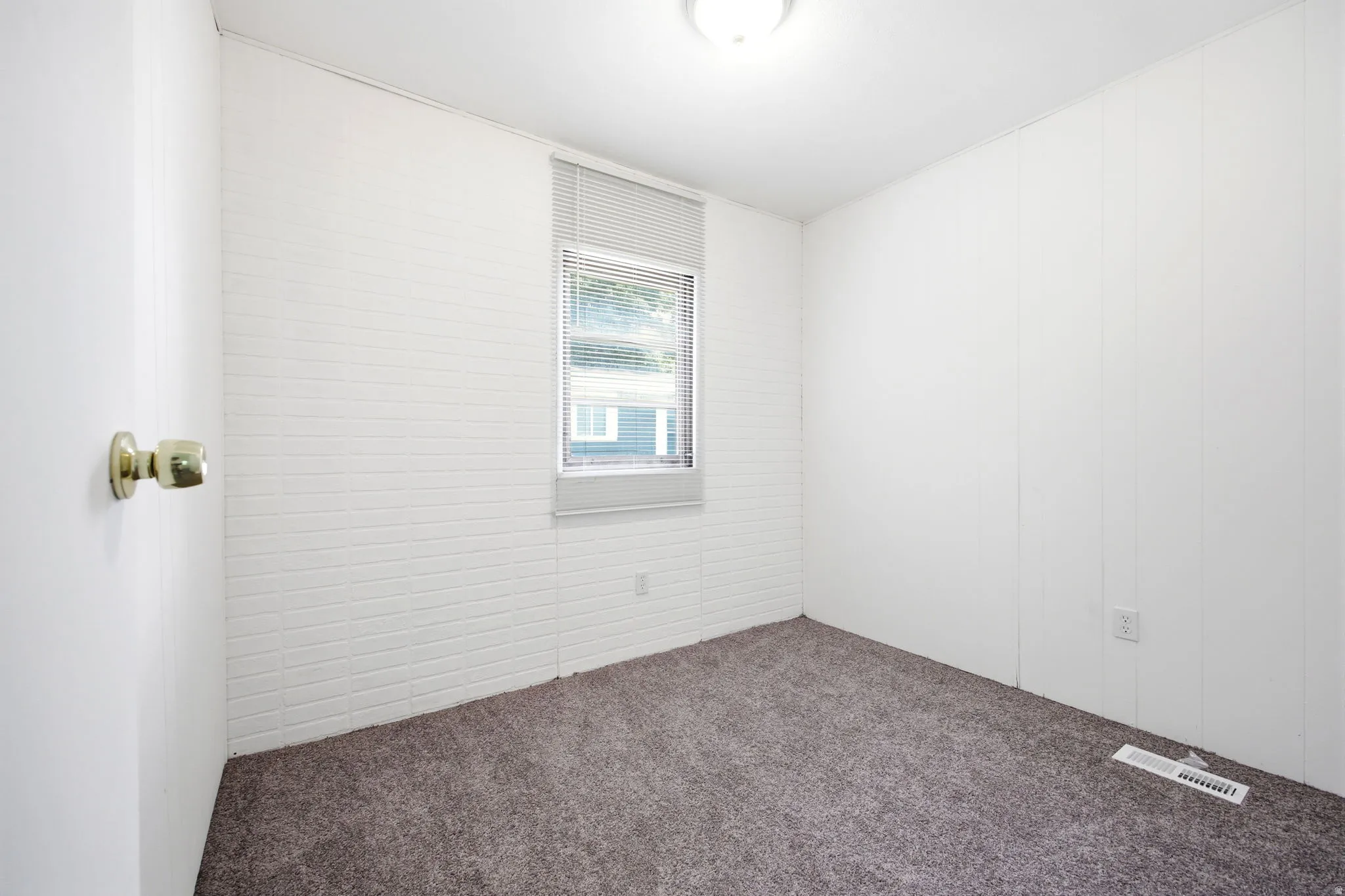 Carpeted room featuring a single window with blinds and white paneling walls