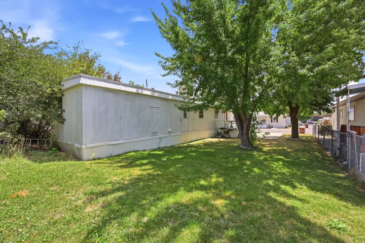 Expansive side yard featuring a manicured lawn and mature shade trees