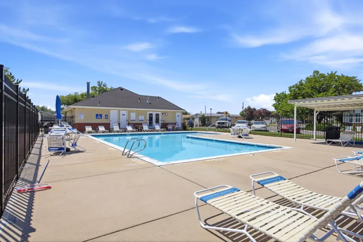 Resort-style swimming pool with spacious concrete decking, lounge seating areas, and a pergola-covered pavilion