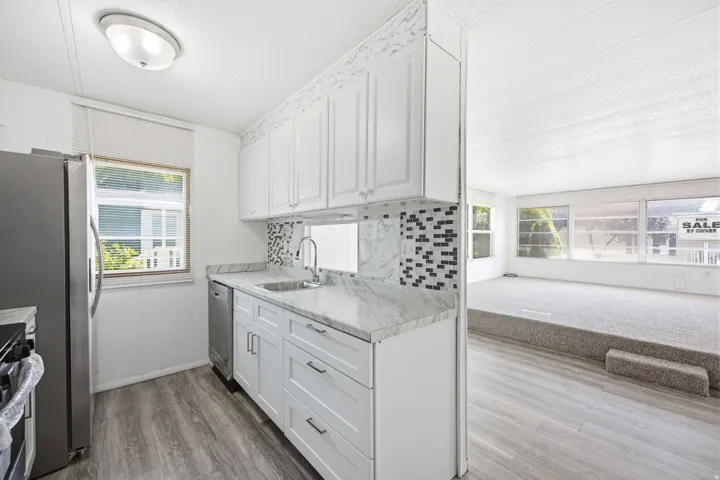 Kitchen featuring white cabinetry, light-toned countertops, a mosaic tile backsplash, and stainless steel appliances