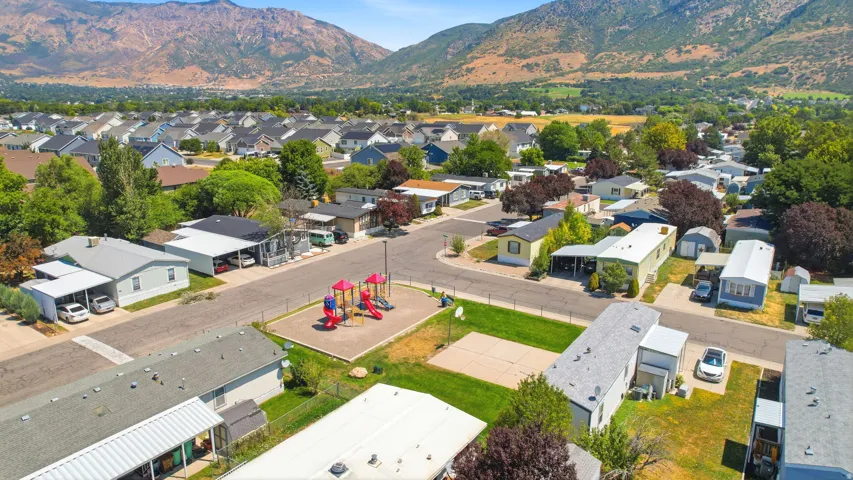 Aerial view of this multi-unit residential property featuring a central recreational area with a playground structure, manicured lawn, and mature landscaping