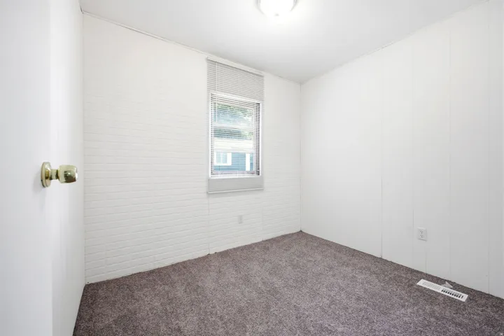 Carpeted room featuring a single window with blinds and white paneling walls