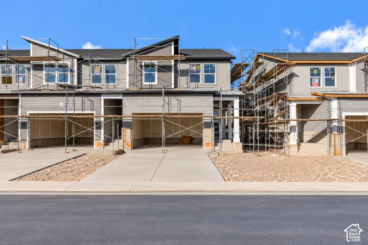Multi-unit residential exterior featuring horizontal siding, stucco finishes, asphalt shingle roofing, and integrated garages with concrete driveways