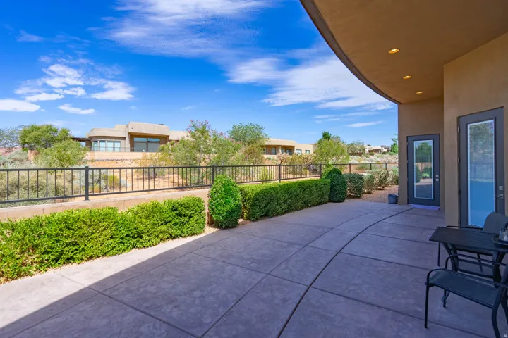 Curved concrete patio with manicured shrubbery and a black metal fence