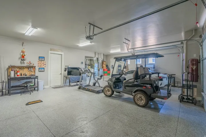 Spacious garage featuring a light gray epoxy floor coating, white overhead garage door, and bright overhead fluorescent lighting