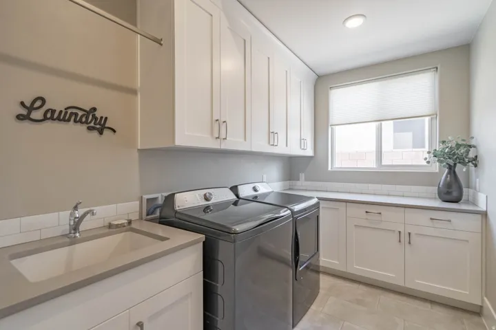 Laundry room featuring white shaker cabinetry, an integrated utility sink, a light-colored countertop, and a subway tile backsplash