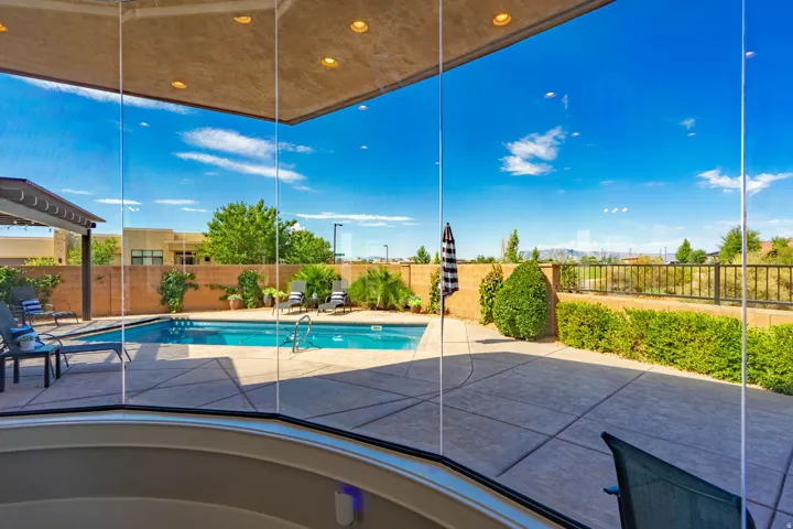 Outdoor entertaining space featuring a clear glass enclosure, recessed ceiling lighting, a swimming pool, a concrete patio, and a covered pergola