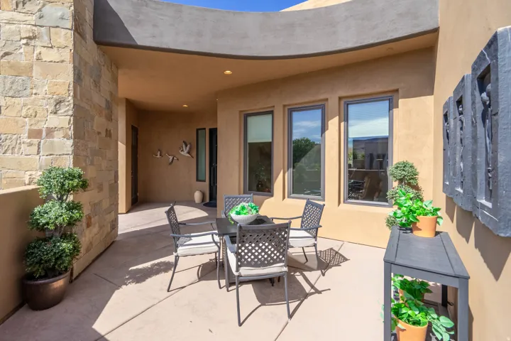 Covered patio featuring a curved stucco wall, stone veneer column, recessed lighting, and multiple windows