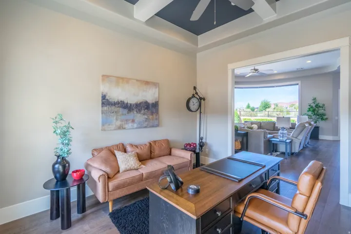 Expansive room featuring dark wood-finish flooring and a tray ceiling with a ceiling fan