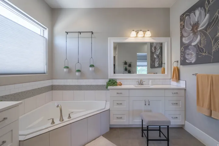 Corner soaking tub with subway tile surround and mosaic accent