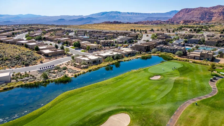Expansive golf course green with a sand bunker and water feature