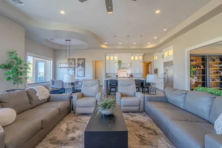 Spacious open-concept living area featuring tray ceilings, recessed lighting, and a large window offering natural light