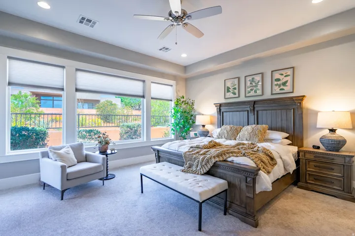 Bright bedroom with a wall of three large windows featuring cellular blinds, providing natural light