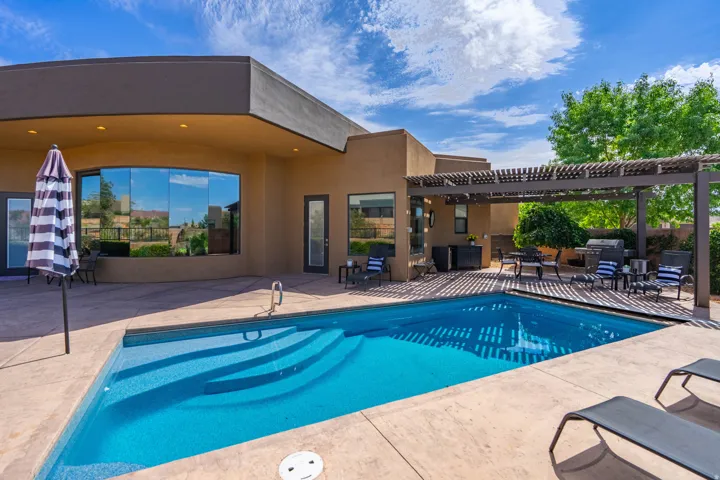 Backyard with a rectangular swimming pool featuring integrated steps and a surrounding concrete patio