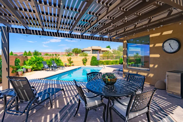 Patio area with a louvered pergola featuring string lighting