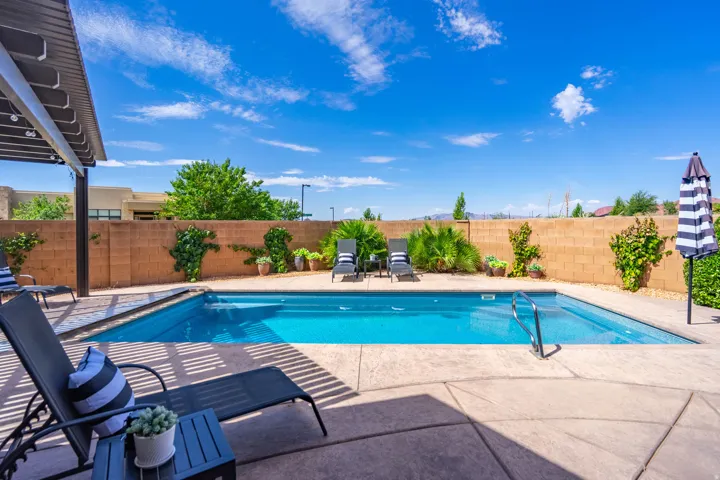 Rectangular in-ground swimming pool with a concrete patio surround, complemented by a covered patio structure