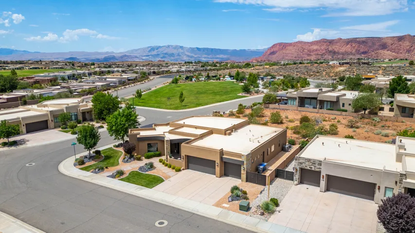 Contemporary stucco residence featuring multiple garage bays, a low-profile roofline, and desert-adapted landscaping