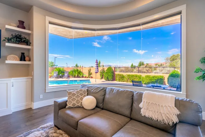 Curved bay window framing an outdoor swimming pool and fenced yard