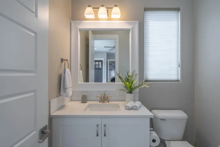 Bathroom featuring a white vanity with an integrated sink, brushed brass faucet, and white subway tile backsplash