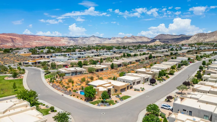Modern residential neighborhood with contemporary architecture, desert landscaping, paved streets, and mountainous terrain in the background
