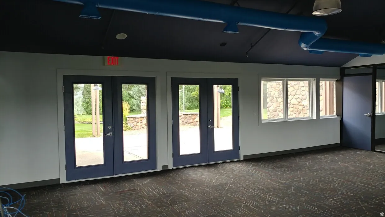 Interior space featuring two sets of double glass-paned doors, a trio of casement windows, and a partially glass-paned door