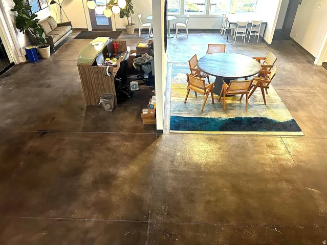 Spacious open-concept interior featuring polished concrete flooring, extensive window banks, and a contemporary pendant light fixture