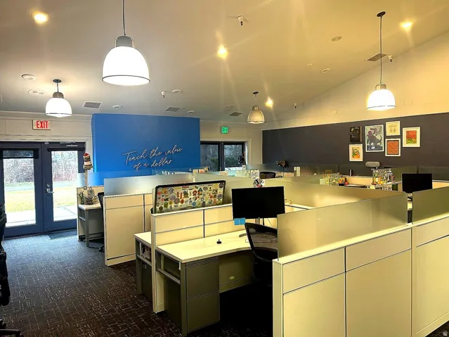 Open-plan office area featuring multiple workstations and pendant lighting