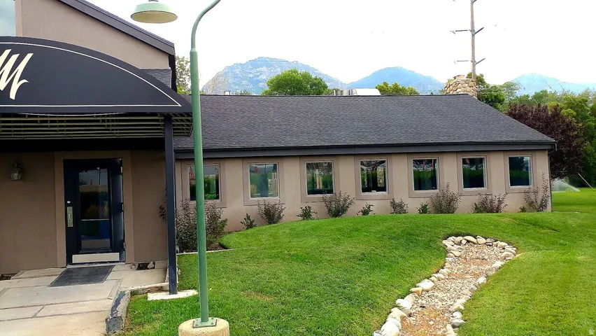 Exterior building featuring a dark asphalt shingle roof, multiple windows, and a stucco finish