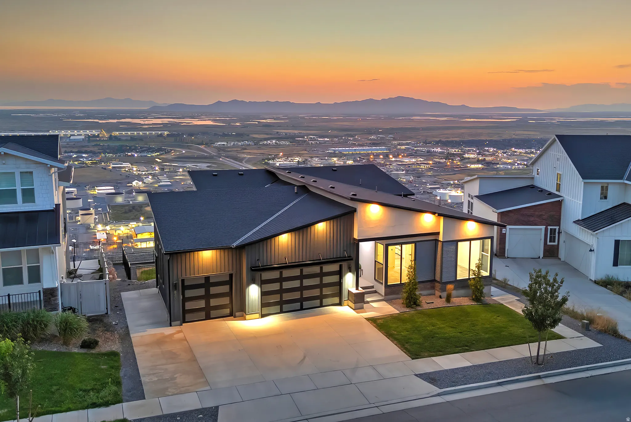 Modern home exterior featuring a dark-toned facade, large picture windows, and a two-car garage with frosted glass panels