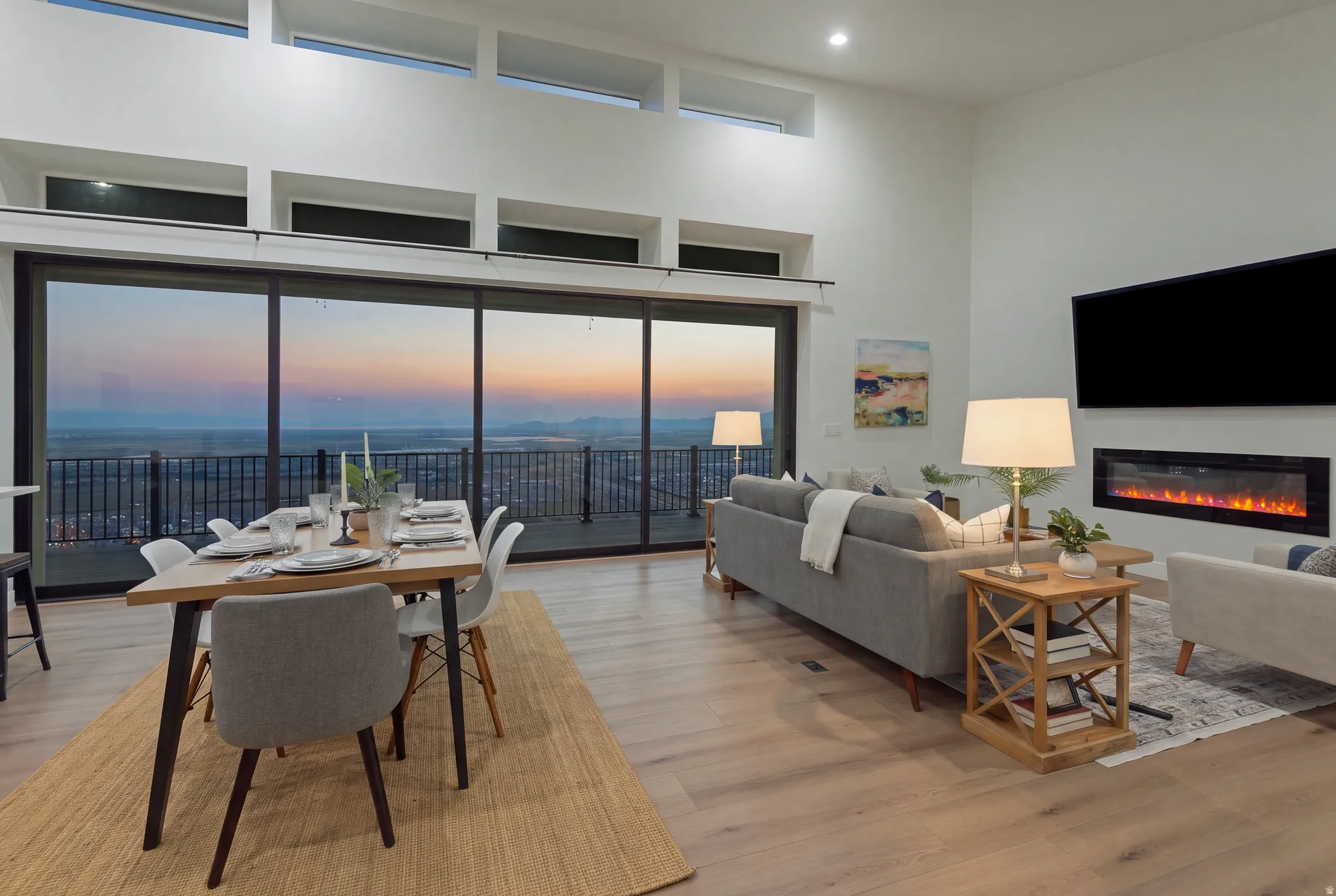 Open-concept living area with expansive floor-to-ceiling sliding glass doors, a linear electric fireplace, high ceilings, and light wood-finish flooring