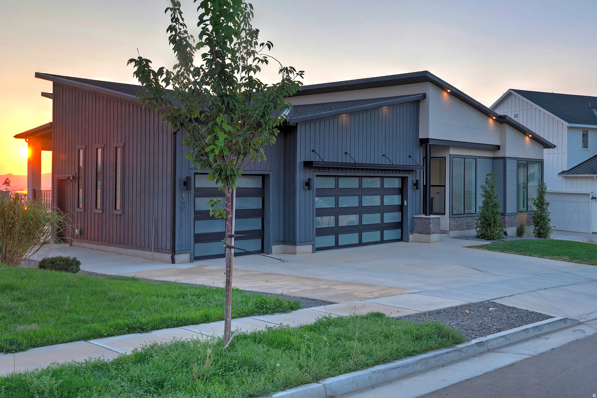 Contemporary home with a sloped roofline, dark vertical siding, and a light-colored stucco facade