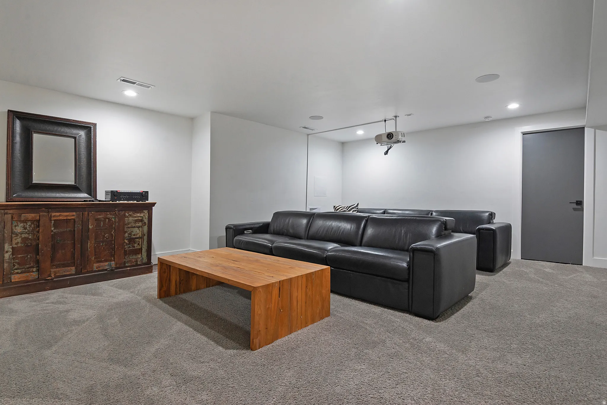 Spacious media room featuring recessed lighting, a ceiling-mounted projector, and integrated ceiling speakers