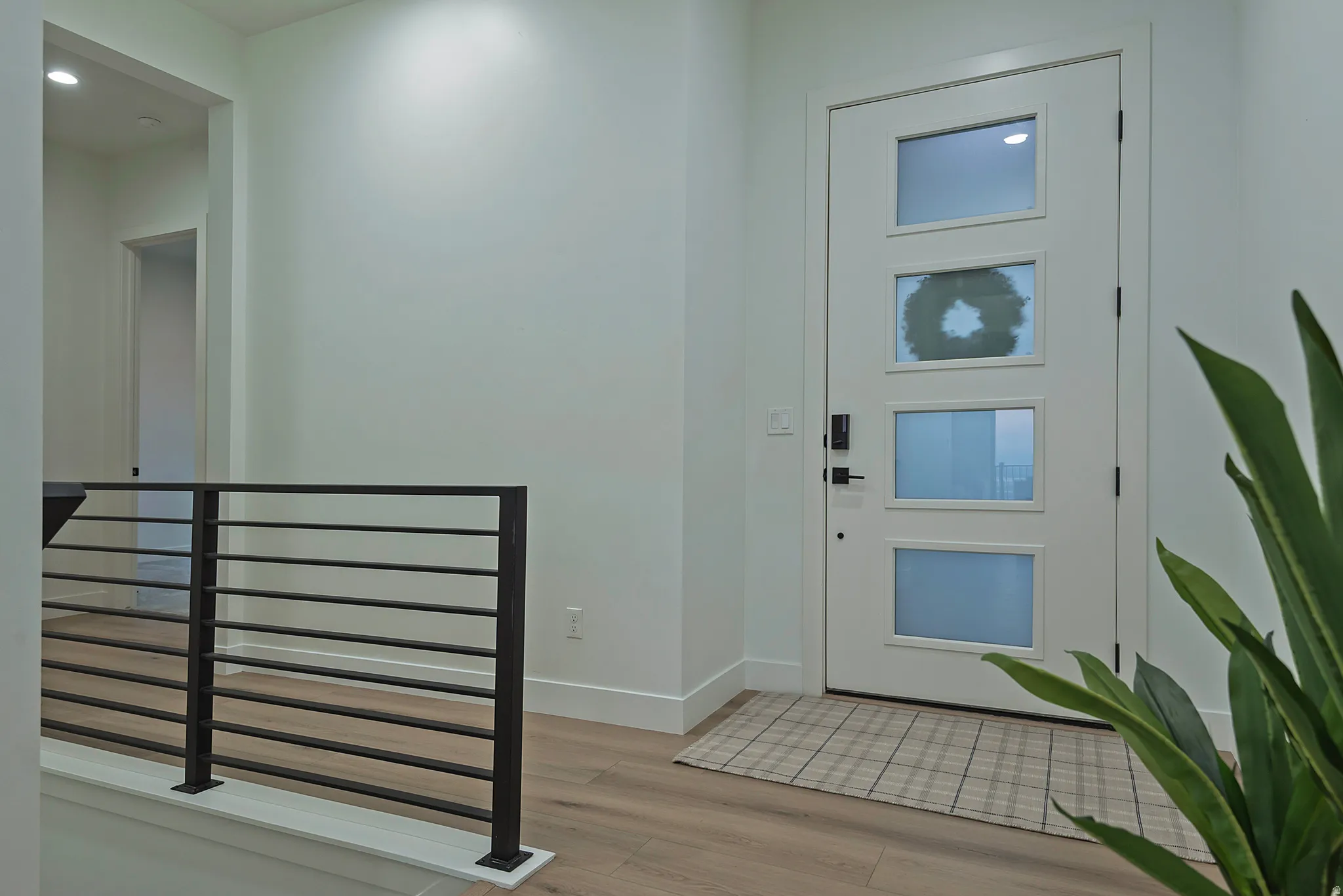 Modern white entry door with four frosted glass panels, black hardware, and smart lock system