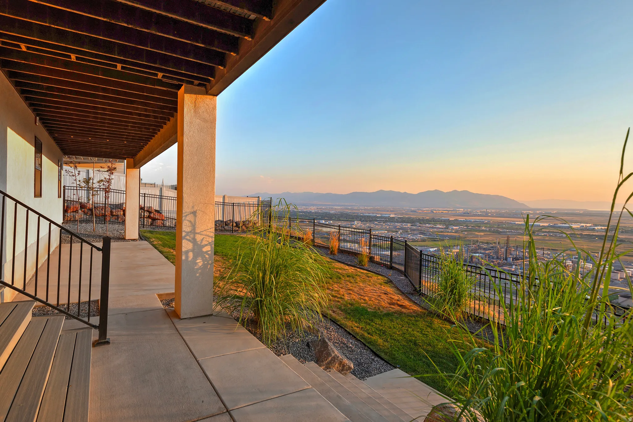 Covered patio with concrete flooring, supported by stucco columns and featuring an exposed wood ceiling