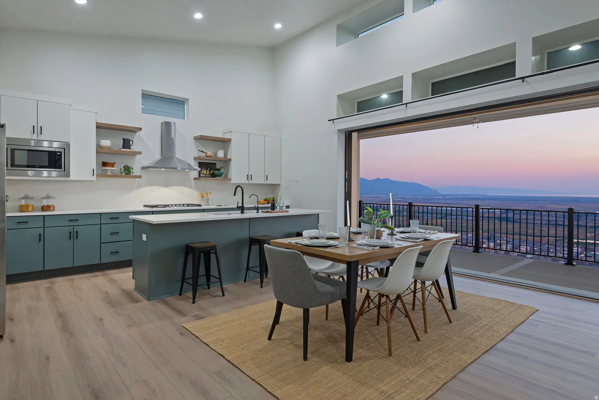 Open-concept kitchen and dining area featuring a sliding glass door system opening to a balcony with mountain and landscape scenery