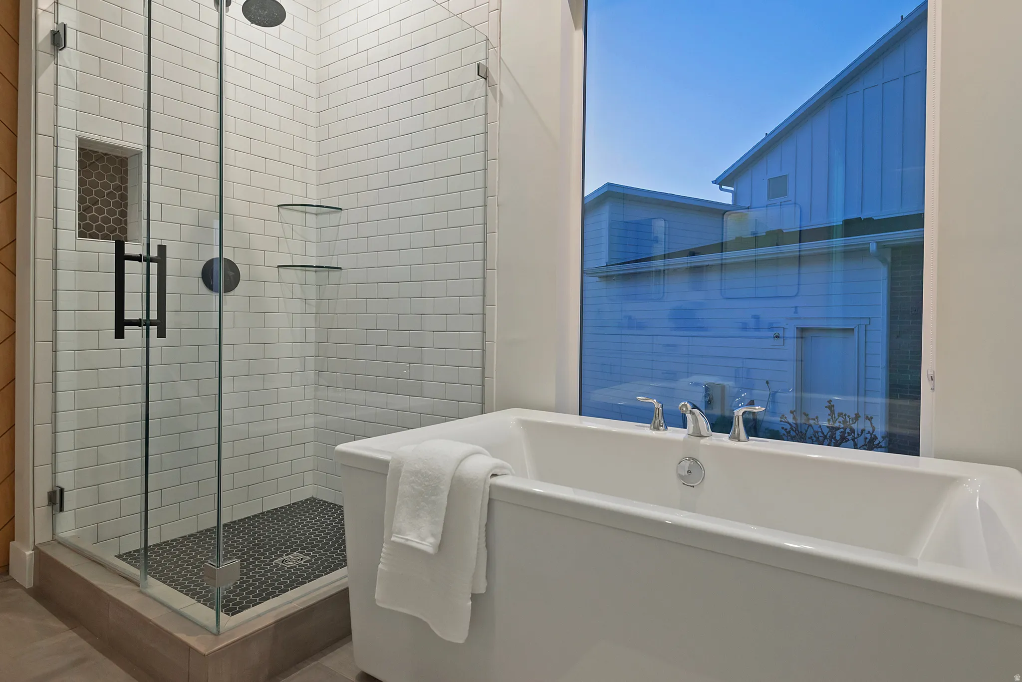 Freestanding soaking tub positioned beneath a large window