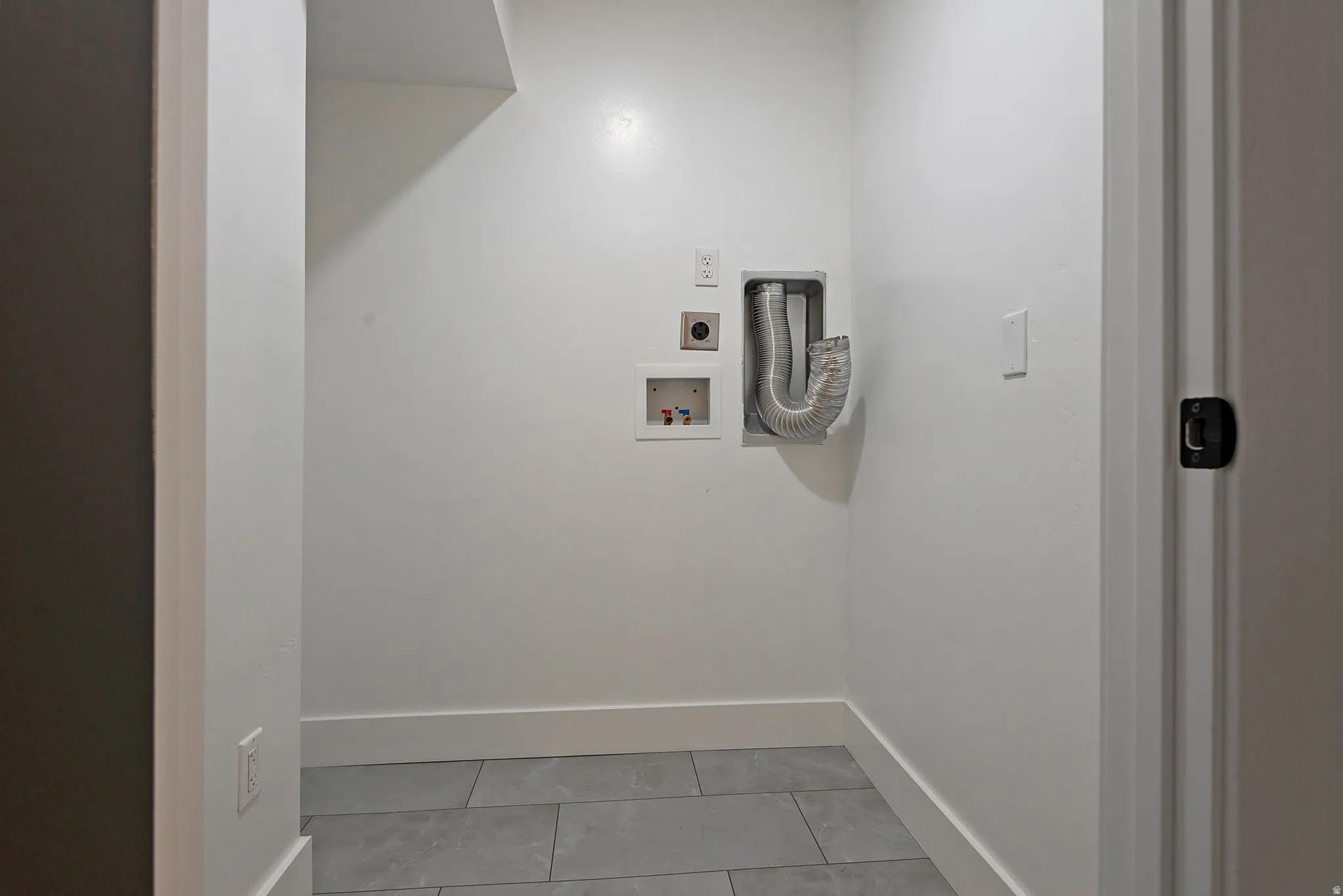 Dedicated laundry area featuring tile flooring, white walls, and appropriate utility hookups