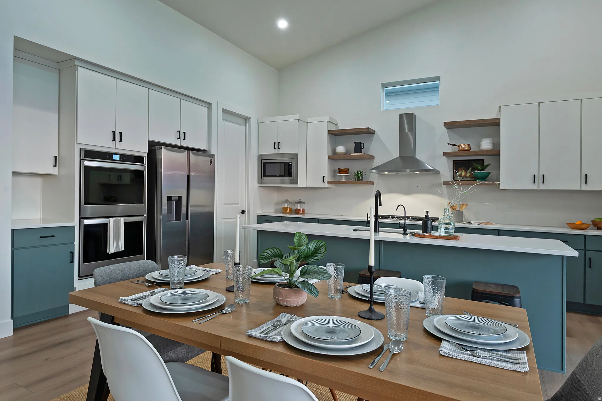 Kitchen featuring a two-tone cabinetry design, stainless steel appliances, a range hood, and an island with a sink