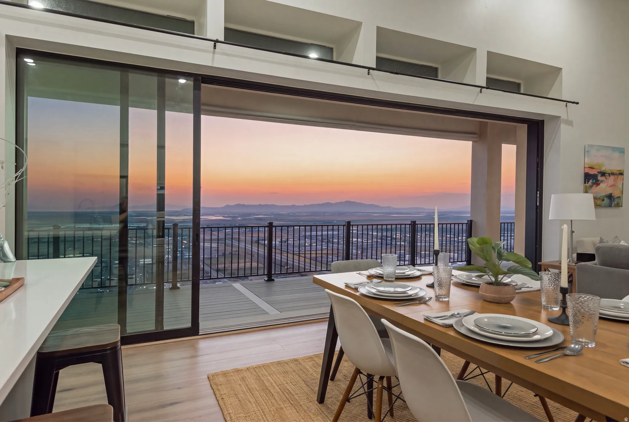 Expansive sliding glass doors opening to a balcony with metal railing, showcasing distant mountains and city lights