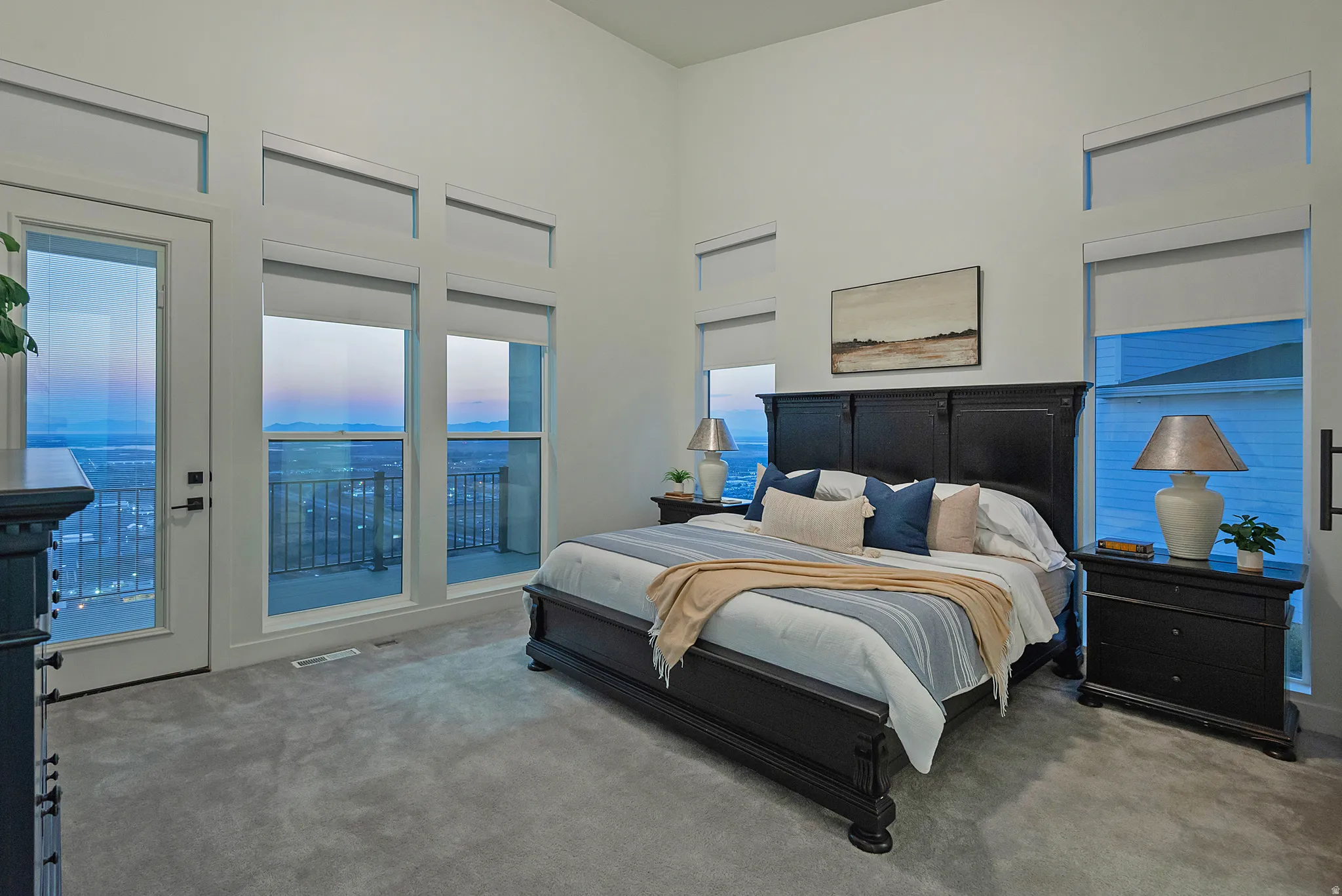 Spacious room featuring vaulted ceilings, plush grey carpeting, and multiple windows with transoms