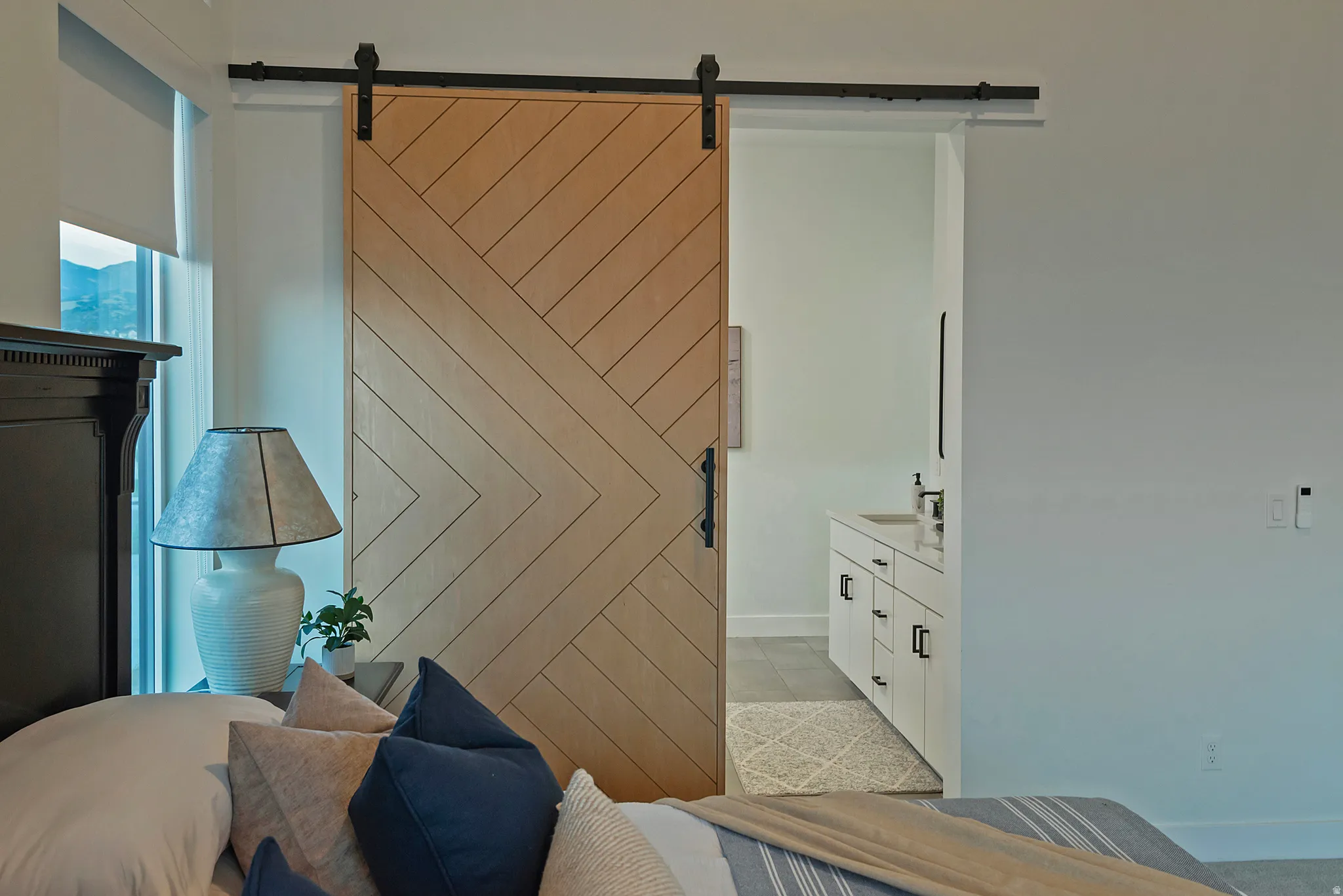 Wood-finish barn door featuring a chevron pattern and matte black hardware