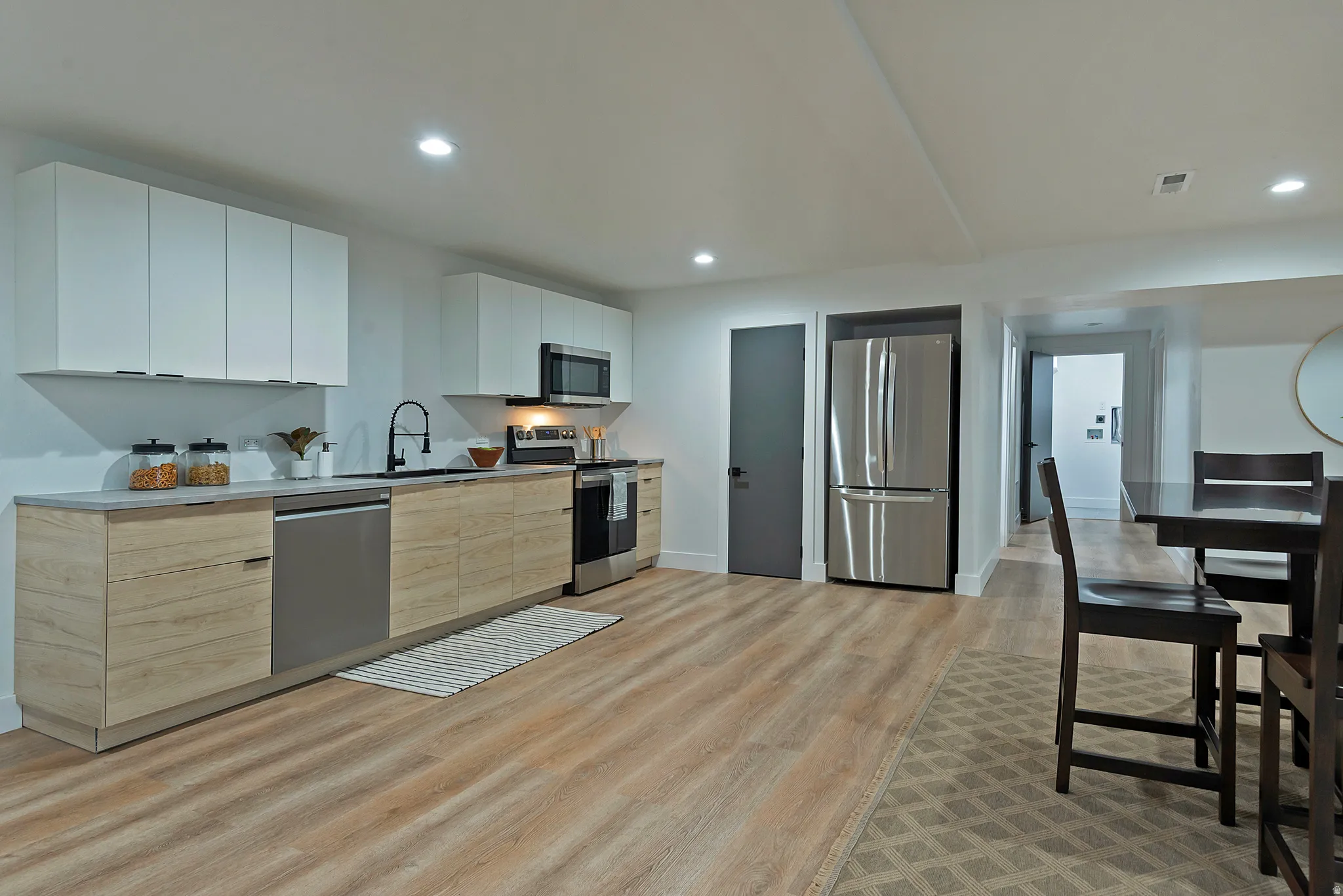 Kitchen featuring wood-finish lower cabinetry, white upper cabinetry, and stainless steel appliances